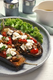 Plate with tasty stuffed eggplants on light table