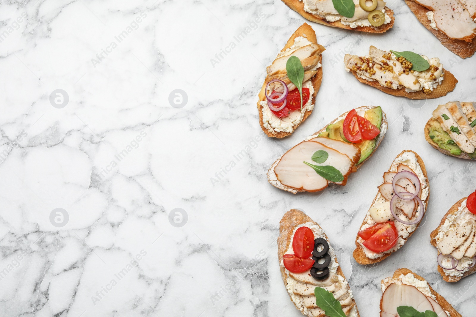 Photo of Different delicious chicken bruschettas on white marble table, flat lay. Space for text