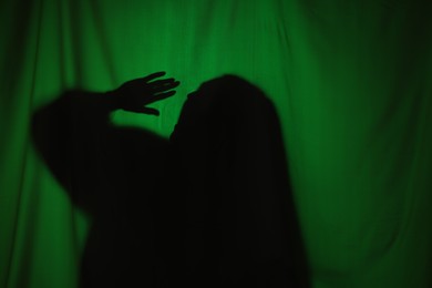 Photo of Silhouette of creepy ghost behind dark green cloth