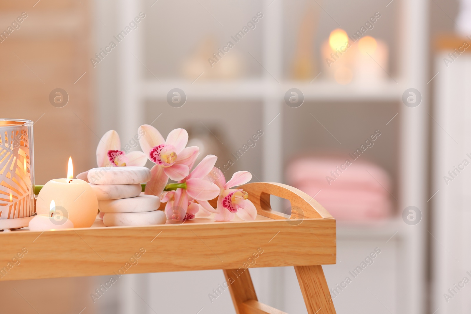 Photo of Composition with candles, flowers and stones on wooden table in spa salon. Space for text