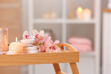 Photo of Composition with candles, flowers and stones on wooden table in spa salon. Space for text