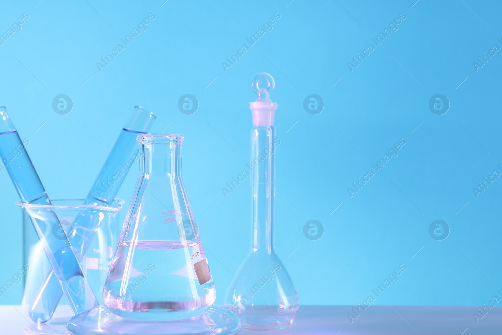 Photo of Laboratory analysis. Different glassware on table against light blue background