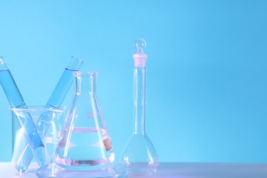 Photo of Laboratory analysis. Different glassware on table against light blue background