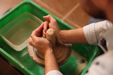 Photo of Man crafting with clay on potter's wheel, closeup