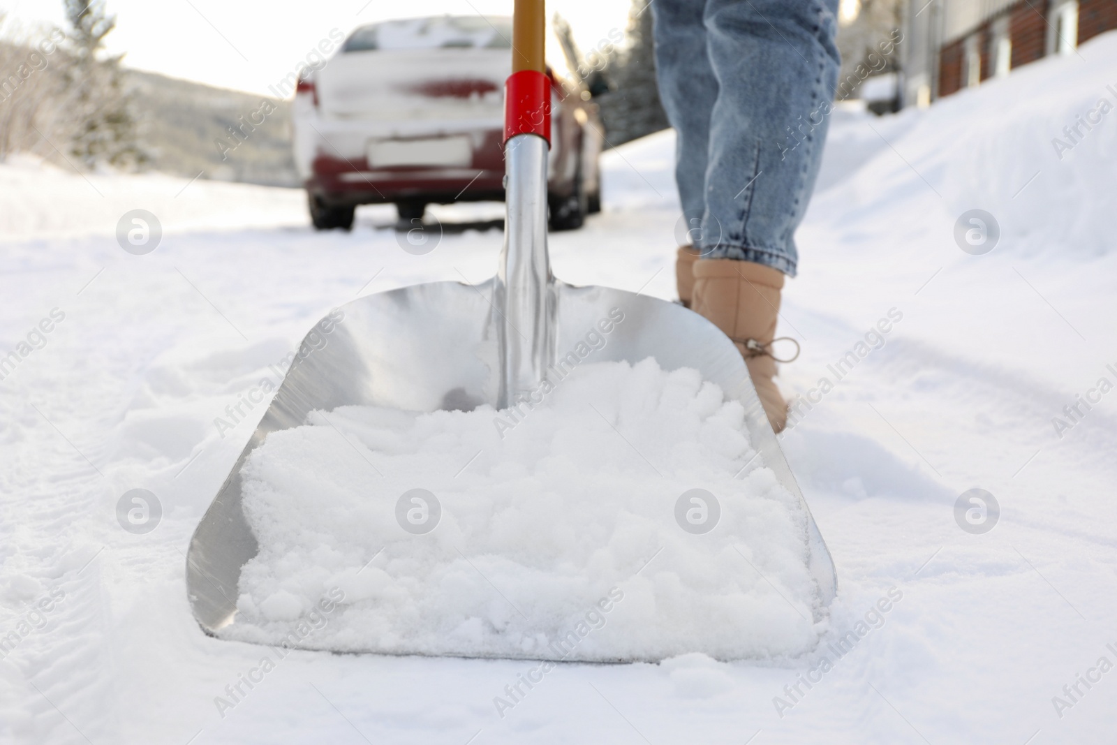 Photo of Woman removing snow with shovel outdoors, closeup