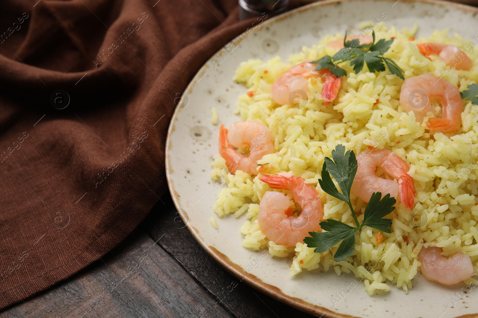 Photo of Delicious risotto with shrimps and parsley on wooden table, closeup. Space for text