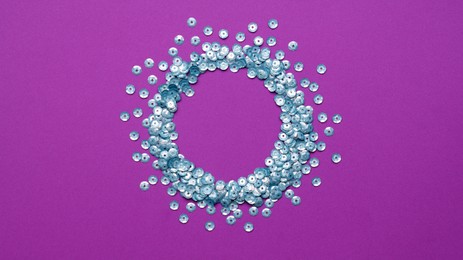 Photo of Circle made of silver sequins on purple background, top view