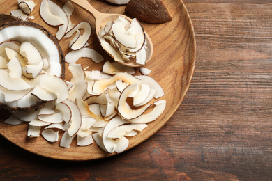 Tasty coconut chips on wooden table, top view