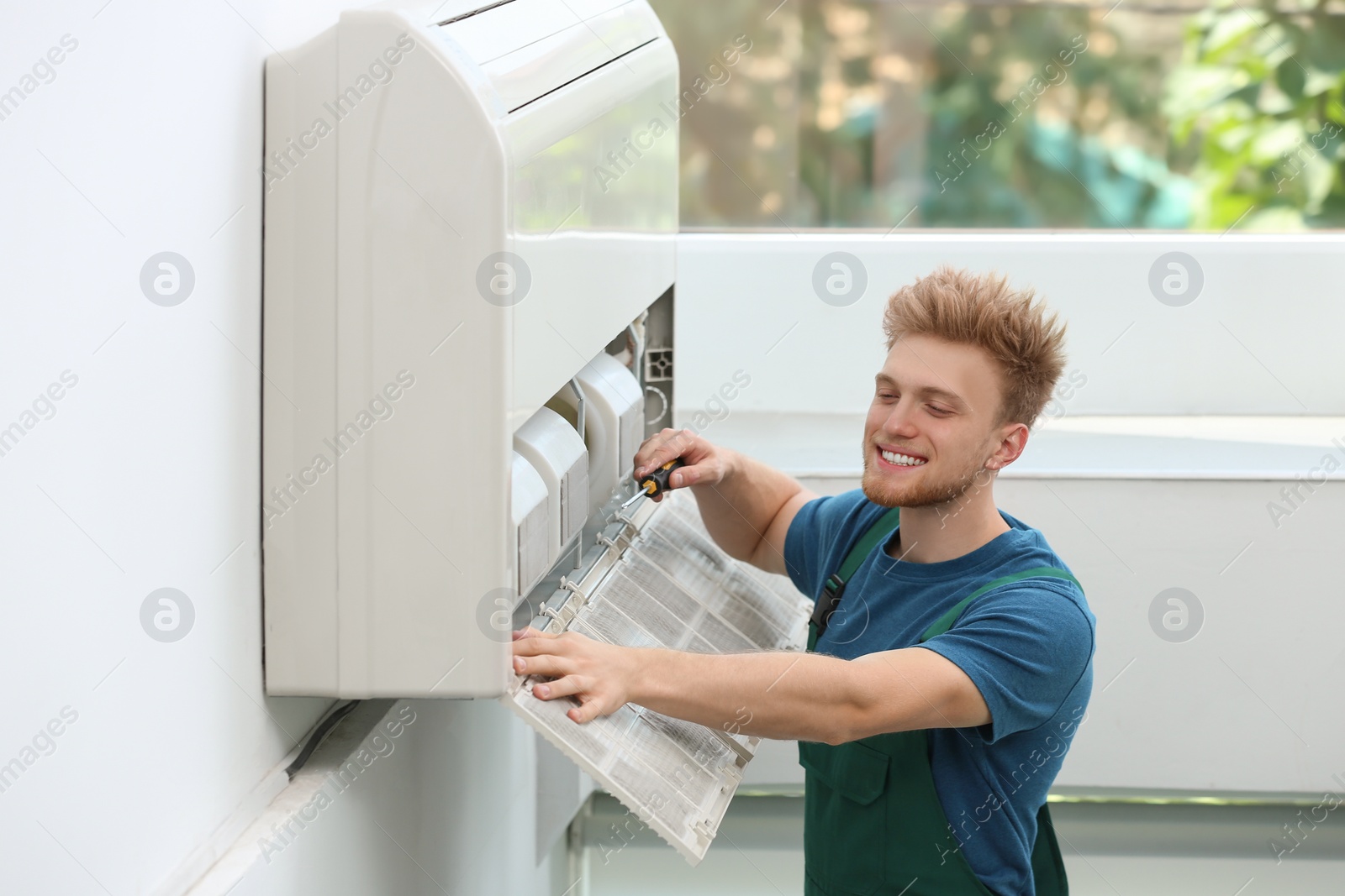 Photo of Professional technician maintaining modern air conditioner indoors