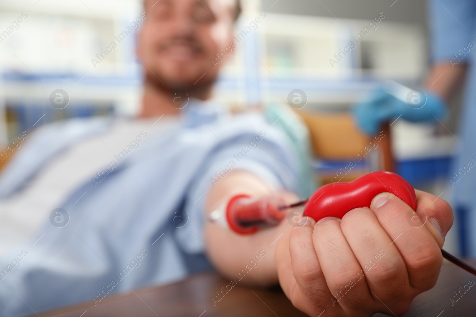 Photo of Young man making blood donation in hospital, focus on hand