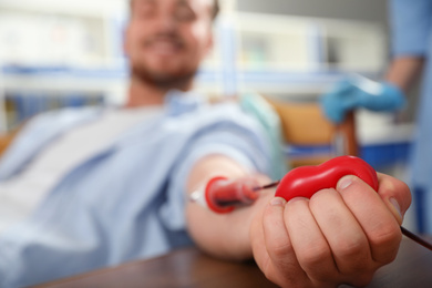 Young man making blood donation in hospital, focus on hand