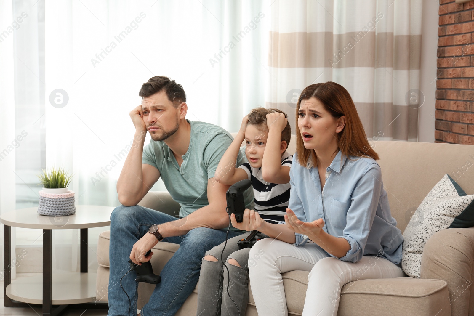Photo of Family playing video games on sofa in living room