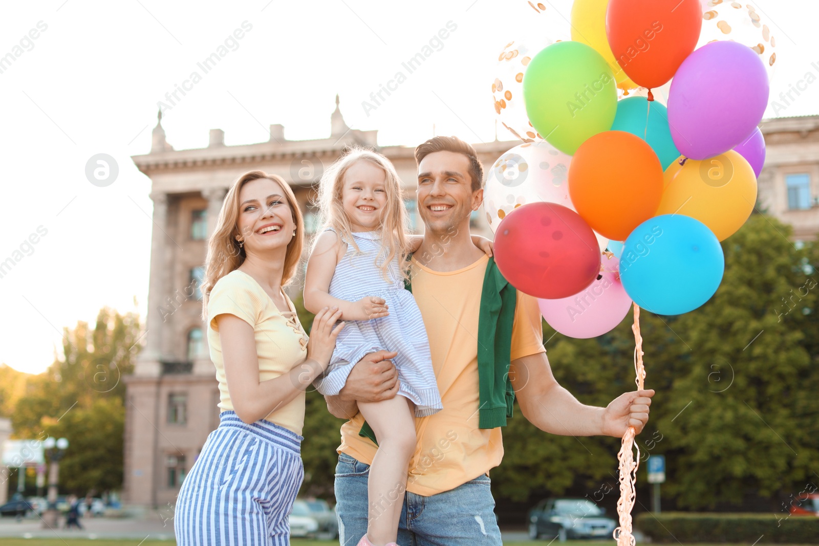 Photo of Happy family with colorful balloons outdoors on sunny day