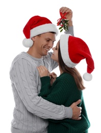 Happy couple standing under mistletoe bunch on white background