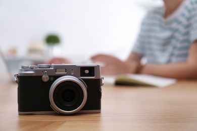 Photo of Woman planning trip at wooden table, focus on vintage camera