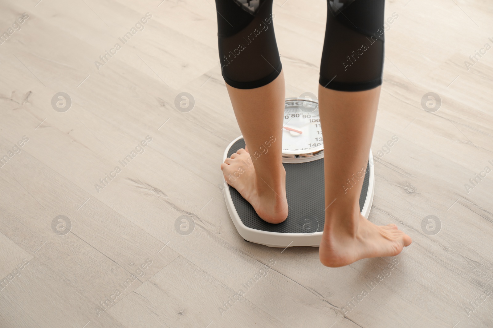 Photo of Woman measuring her weight using scales on wooden floor. Healthy diet