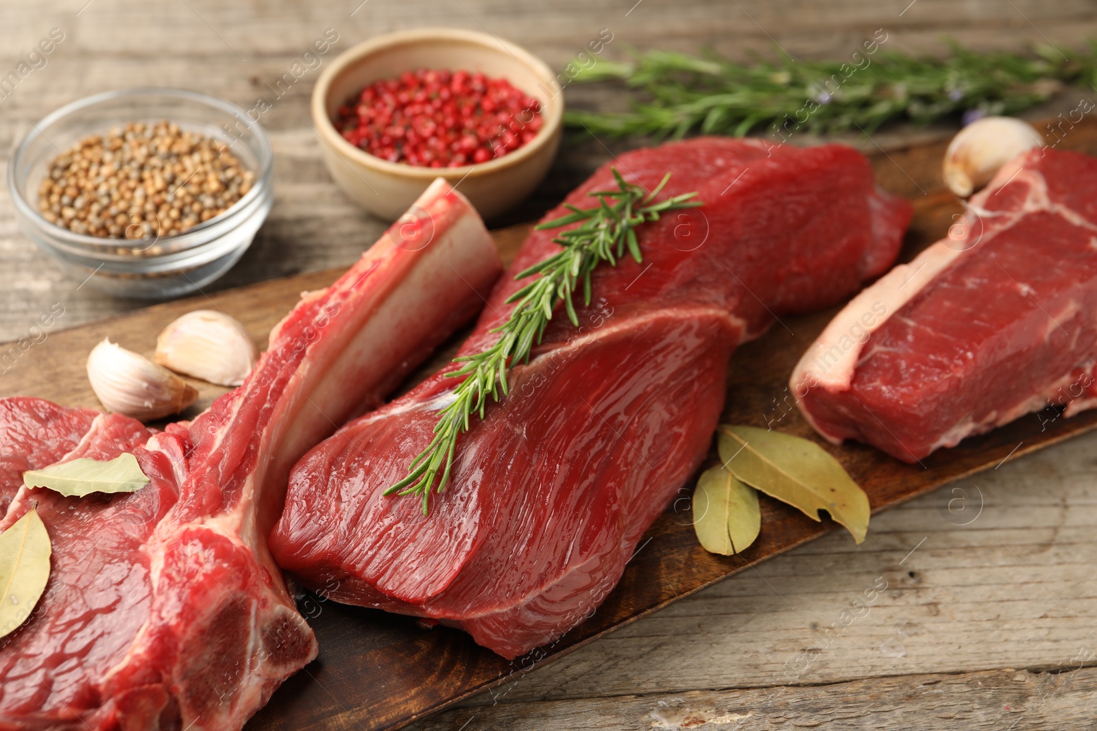 Photo of Pieces of raw beef meat and spices on wooden table