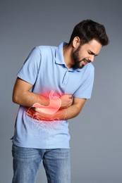 Man suffering from stomach ache on grey background. Illustration of unhealthy gastrointestinal tract