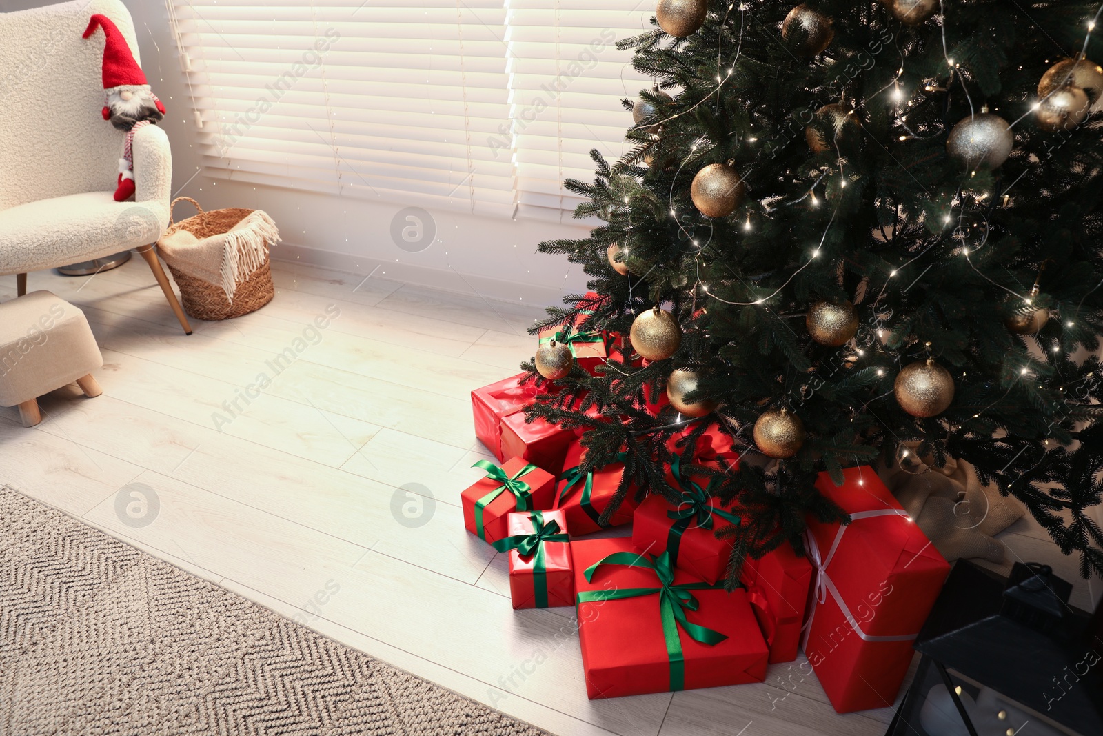 Photo of Beautifully wrapped gift boxes under Christmas tree in room, above view