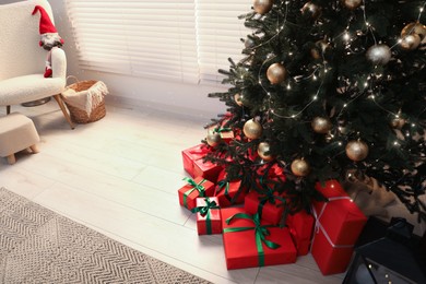 Beautifully wrapped gift boxes under Christmas tree in room, above view