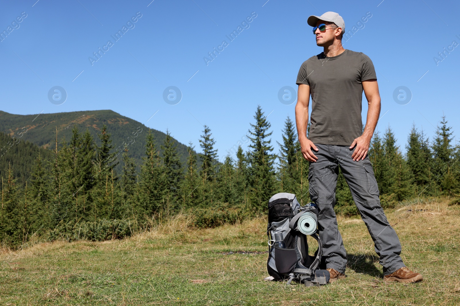 Photo of Tourist with backpack in mountains on sunny day. Space for text