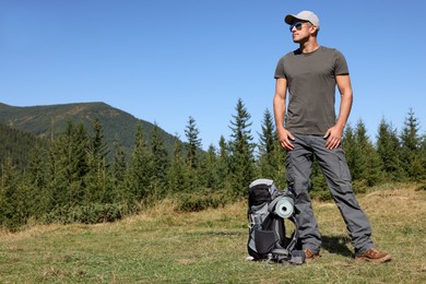 Tourist with backpack in mountains on sunny day. Space for text