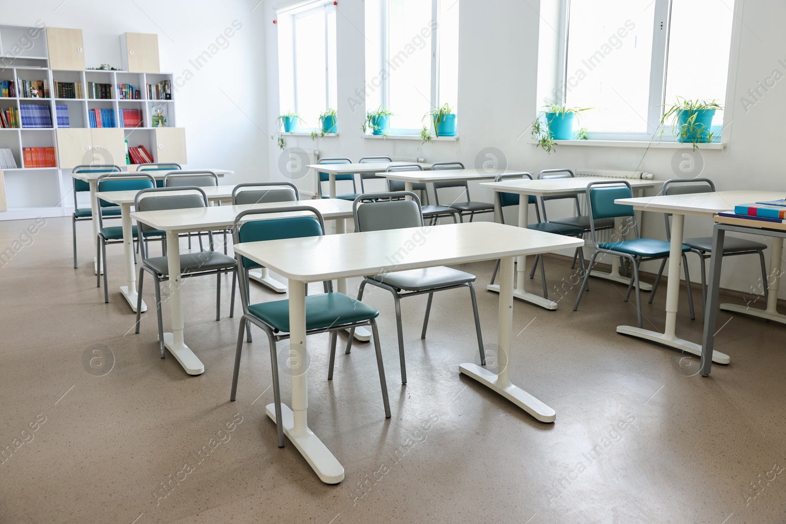 Photo of Empty school classroom with desks, windows and chairs