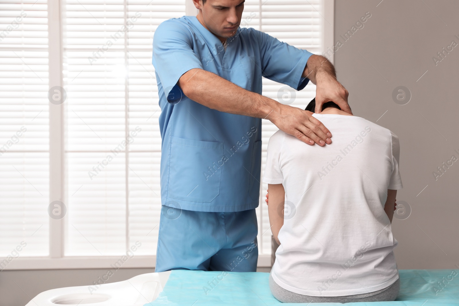 Photo of Orthopedist examining woman's neck in clinic. Scoliosis treatment