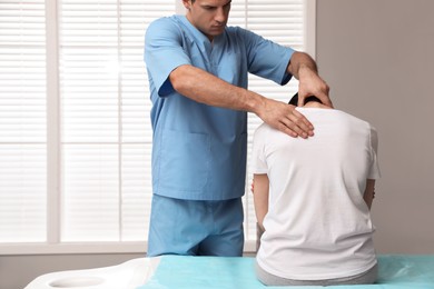 Orthopedist examining woman's neck in clinic. Scoliosis treatment