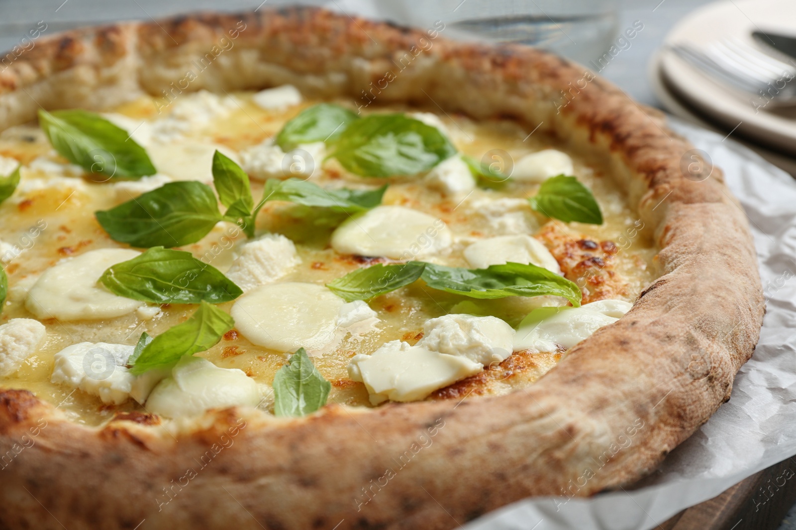 Photo of Delicious hot cheese pizza with basil on table, closeup