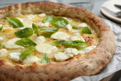 Delicious hot cheese pizza with basil on table, closeup