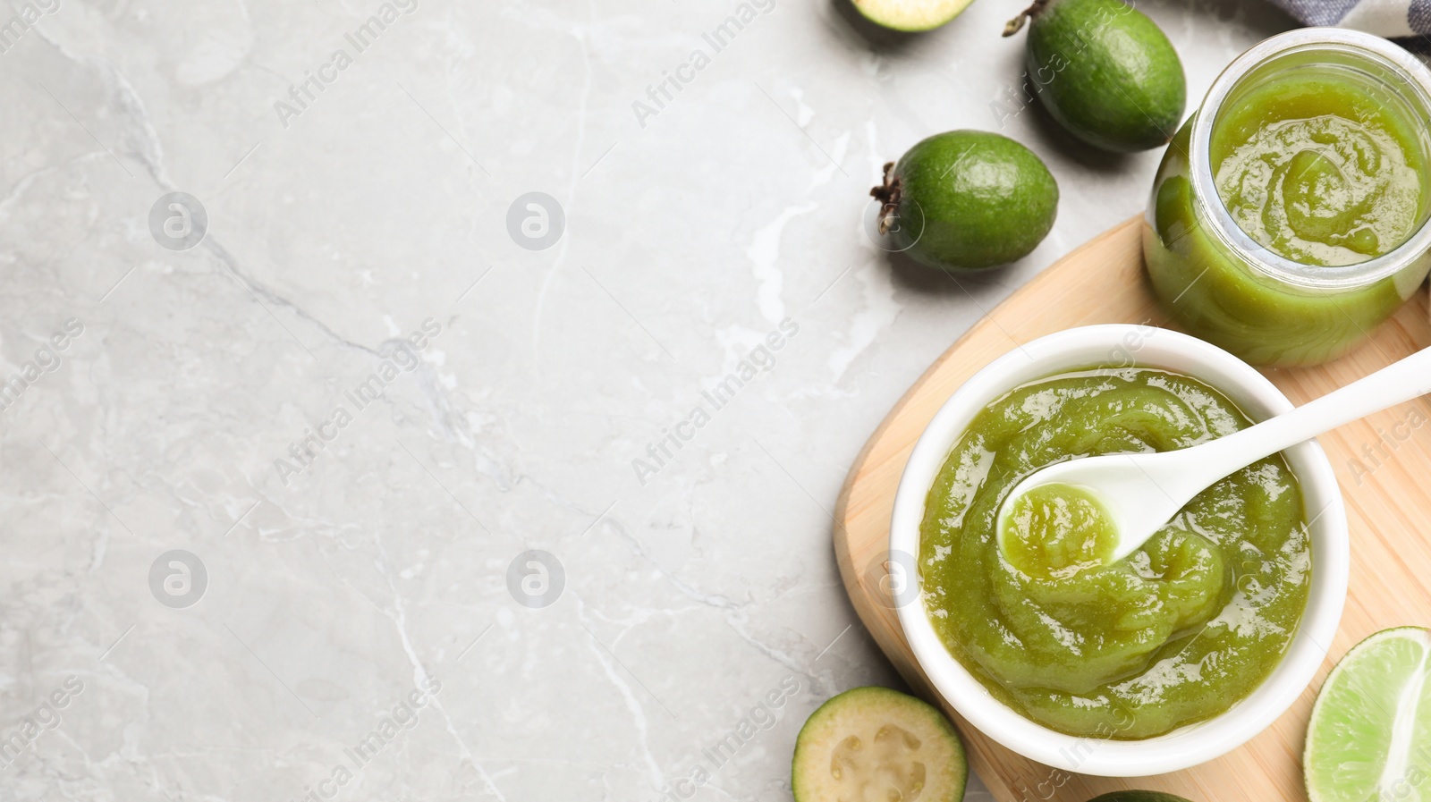 Image of Feijoa jam and fruit on light grey marble table, flat lay with space for text. Banner design