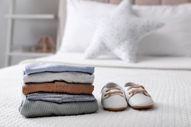 Photo of Stack of baby boy's clothes and shoes on bed at home, space for text