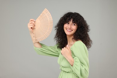 Photo of Happy woman holding hand fan on light grey background. Space for text