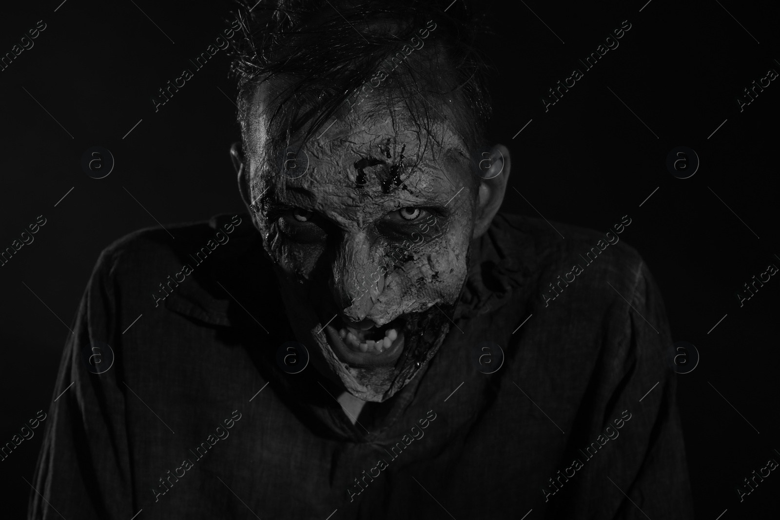 Photo of Scary zombie on dark background, black and white effect. Halloween monster