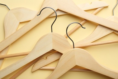Photo of Wooden hangers on pale yellow background, top view