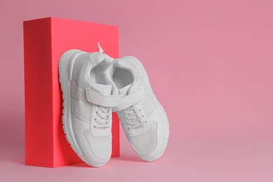 Photo of Pair of stylish sneakers and box on pink background. Space for text