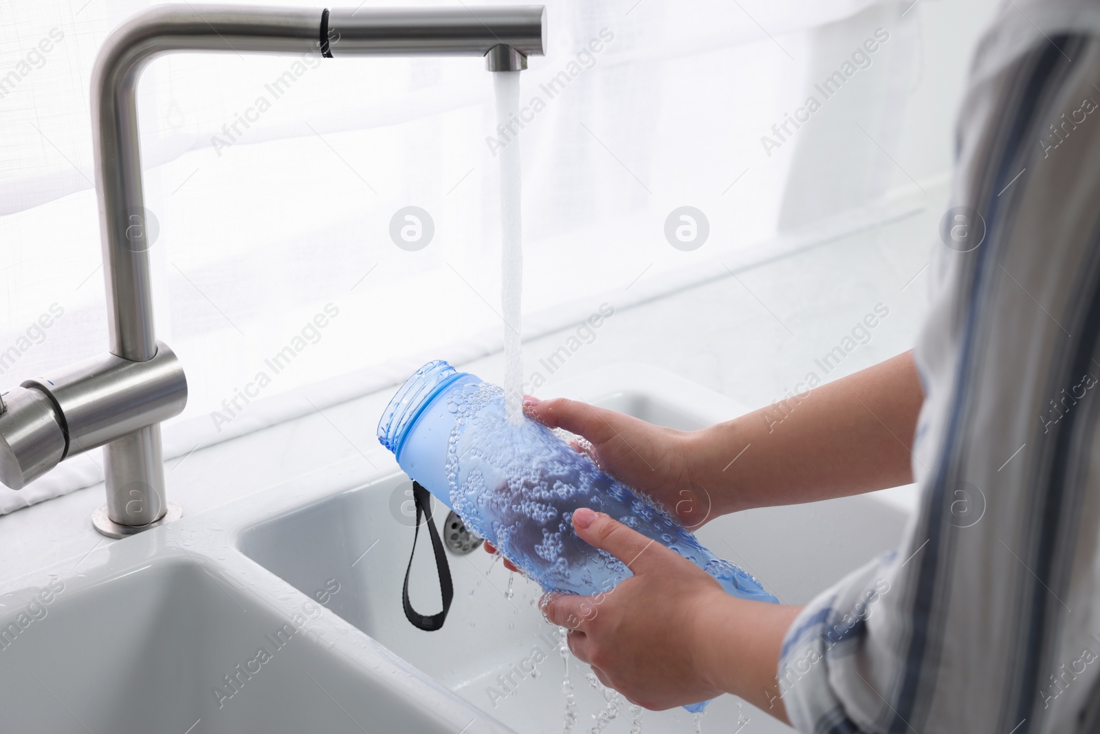 Photo of Woman washing thermo bottle in kitchen, closeup