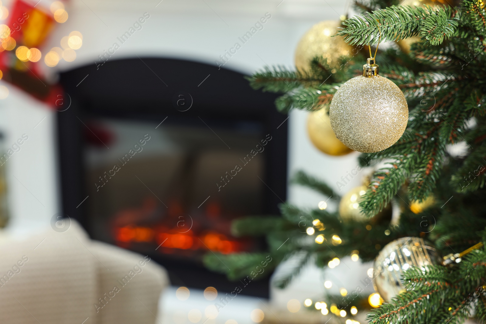 Photo of Beautiful Christmas baubles hanging on fir tree branch in room, space for text