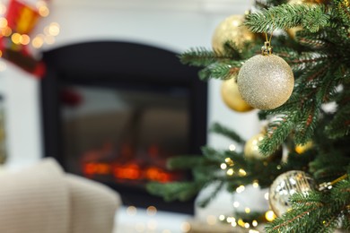 Beautiful Christmas baubles hanging on fir tree branch in room, space for text