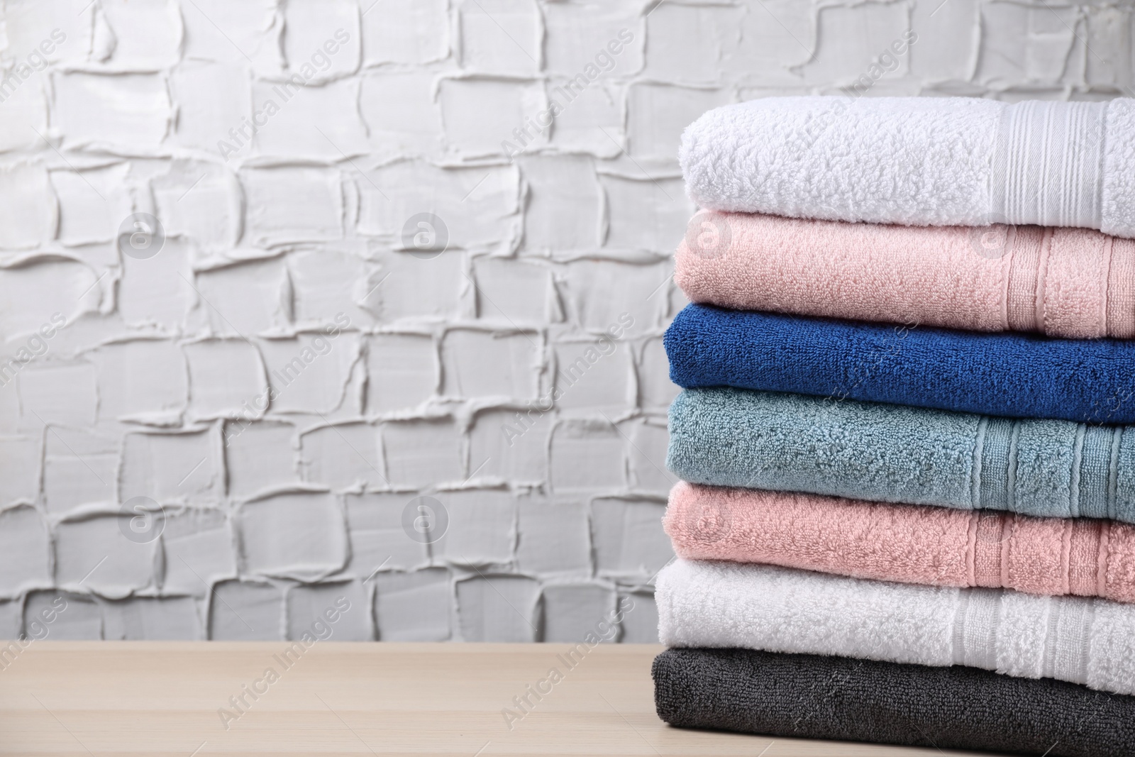 Photo of Stacked soft terry towels on wooden table. Space for text
