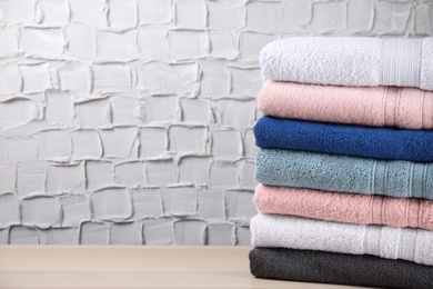 Photo of Stacked soft terry towels on wooden table. Space for text