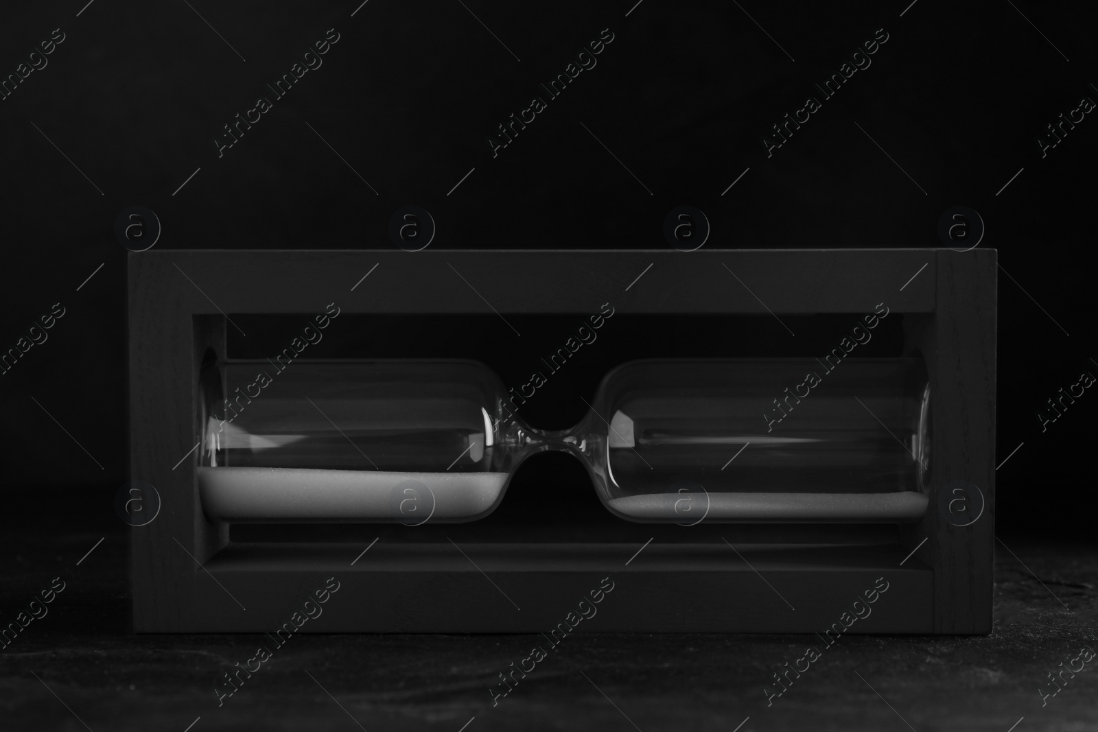 Photo of Sandglass on table against black background. Pareto principle concept