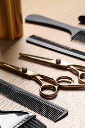 Photo of Hairdresser tools. Different scissors and combs on wooden table in salon, closeup