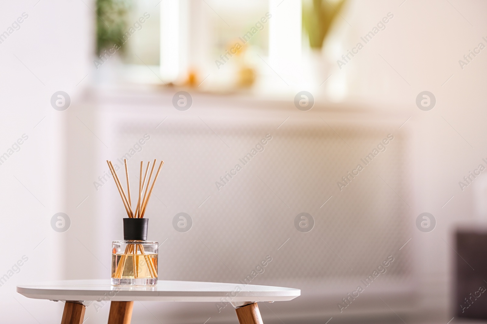 Photo of Aromatic reed air freshener on table against blurred background