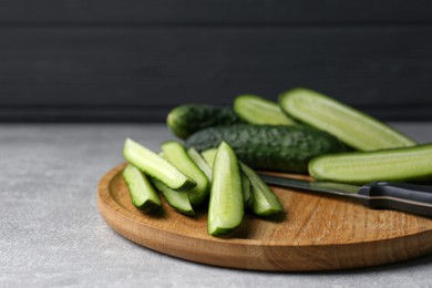 Photo of Whole and cut fresh ripe cucumbers on grey table