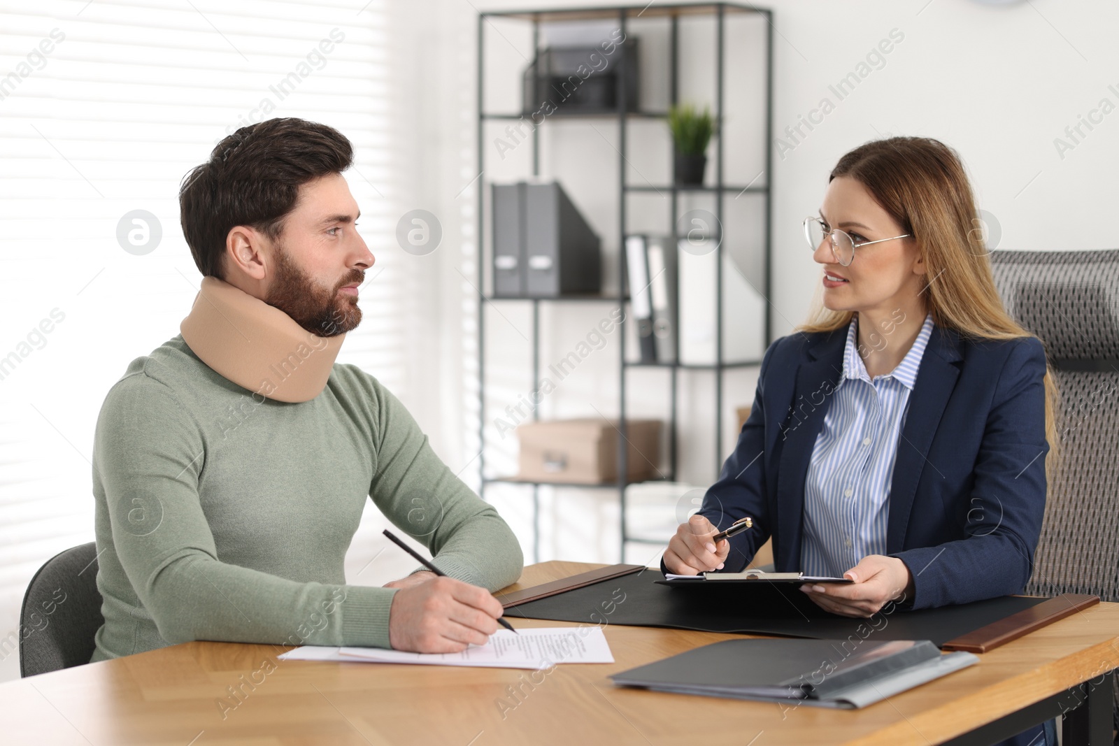 Photo of Injured man signing document in lawyer's office