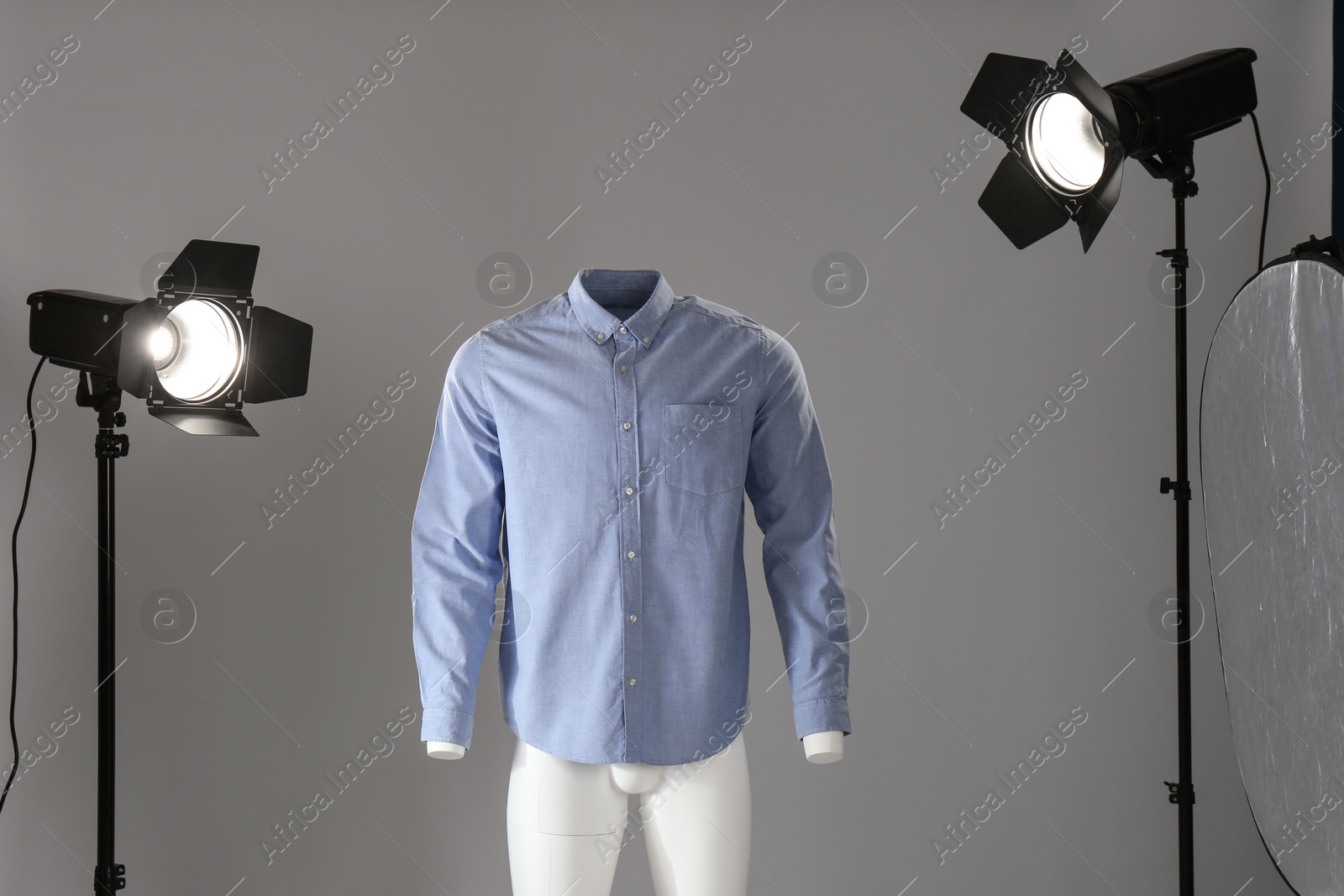 Photo of Stylish clothes on ghost mannequin and professional lighting equipment in modern studio. Fashion photography