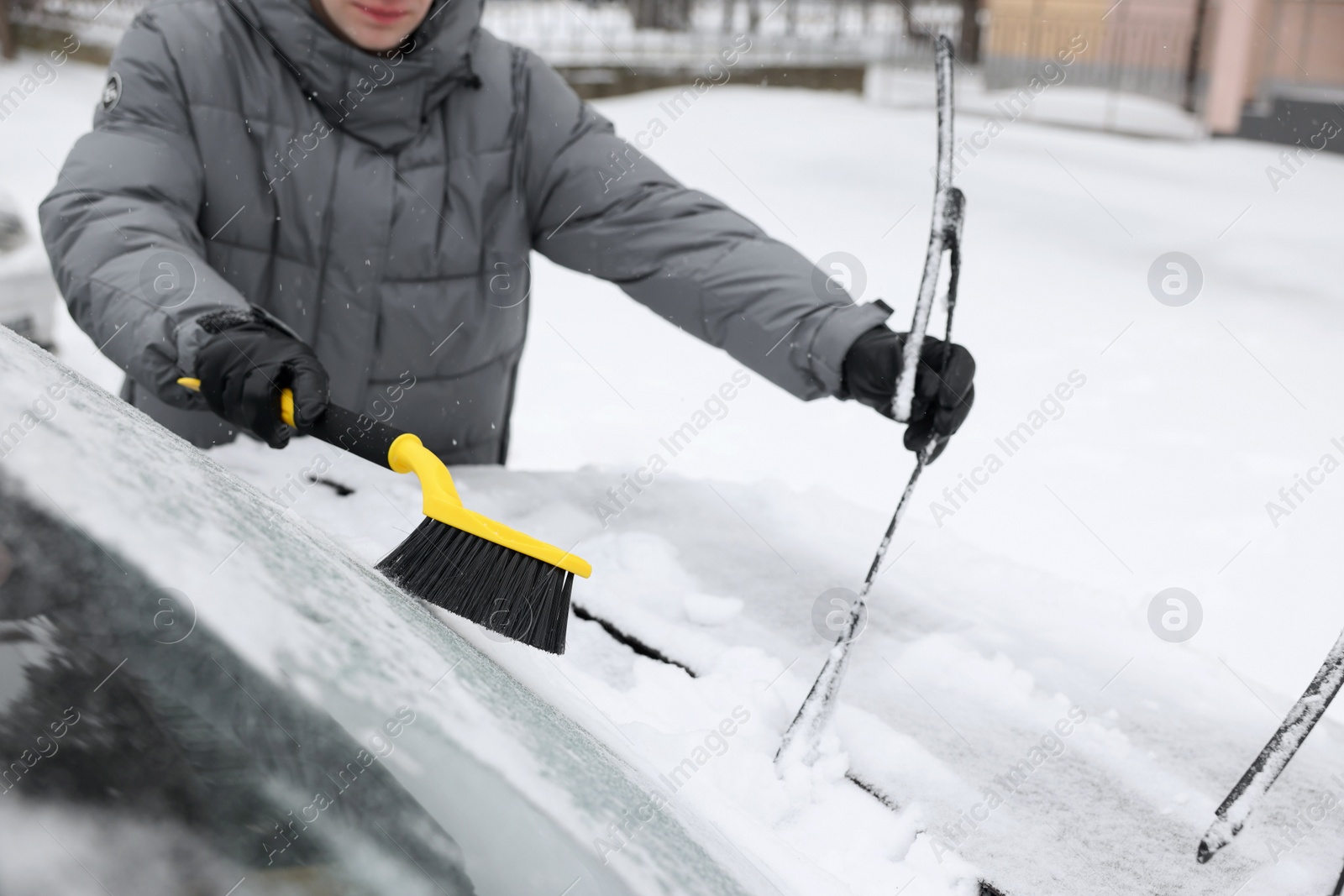 Photo of Man cleaning snow from car windshield outdoors, closeup