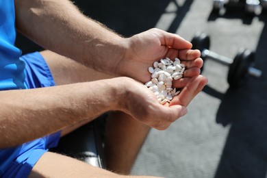 Photo of Sportsman with handful of pills in gym, closeup. Doping concept